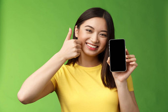 特写镜头满意可爱的亚洲女孩给积极的反馈翘拇指显示智能手机屏幕介绍太棒了应用程序推荐好应用程序吹牛<strong>打分</strong>数游戏