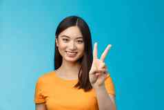快乐的友好的亚洲女人黄色的t恤微笑广泛的显示数量赢得的地方微笑快乐使外卖订单书坐在站蓝色的背景