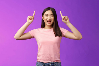 有魅力的好看的活泼的微笑亚洲女孩介绍产品指出手指前广告咧着嘴笑露出牙齿的兴奋告诉好新闻<strong>分享链接</strong>紫色的背景