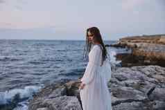 女人白色衣服漫步海洋石头海滩