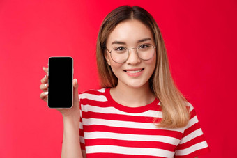 特写镜头可爱的亚洲金发碧眼的女孩促进智能手机应用程序女博主显示个人社会媒体页面持有电话相机幸福的微笑推荐设备吹牛分数红色的背景
