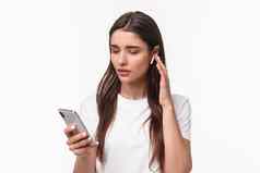 特写镜头肖像现代年轻的女人t恤无线耳机听音乐播客挑选首歌移动电话发短信朋友调用人白色背景