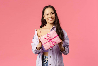 女孩现在肖像时尚的漂亮的年轻的亚洲女持有包装礼物盒子微笑相机邀请<strong>生日</strong>聚会，派对站粉红色的背景