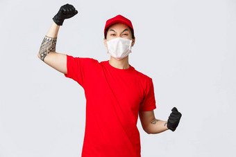 快乐的热情的交付的家伙红色的t恤帽穿医疗面具保护手套提高手高喊<strong>万岁</strong>庆祝成功鼓励订单在线