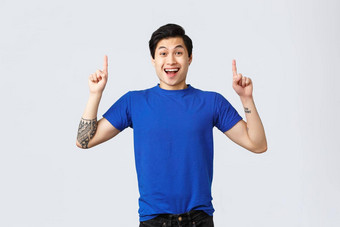 情绪人生活方式广告概念欢乐快乐英俊的亚洲男人。<strong>蓝色</strong>的t恤指出手指微笑美妙的<strong>新闻</strong>灰色背景