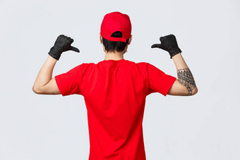 回来视图交付男人。红色的帽t恤穿保护手套流感大流行科维德指出显示公司标志统一的确保快交付快递购物概念