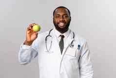 医疗保健医学健康的生活方式概念好看的微笑非裔美国人医生建议保持适合吃水果由维生素显示苹果病人灰色背景