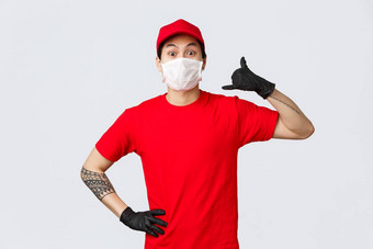 调用快安全交付兴奋亚洲交付的家伙红色的帽t恤穿保护手套医疗面具显示电话标志脸做广告快递公司服务
