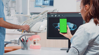 牙医垂直持有智能手机绿色屏幕