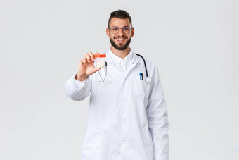 医疗保健工人医疗保险流感大流行科维德概念英俊的快乐的医生微笑相机穿医疗白色外套眼镜推荐<strong>药物治疗</strong>显示药片