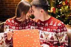概念假期浪漫惊喜快乐男人。使圣诞节礼物亲爱的女人肖像浪漫的夫妇开放现在礼物盒子晚上装饰圣诞节树