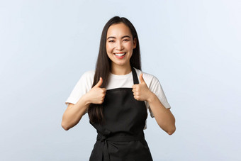 咖啡商店小业务启动概念快乐的微笑亚洲女咖啡馆工作人员咖啡师工作显示翘拇指穿围裙可爱的女孩员工推荐访问不错的的地方好食物