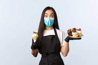 科维德社会距离小咖啡商店业务防止病毒概念兴奋可爱的亚洲女咖啡师推荐夏天菜单甜点持有松饼穿医疗面具