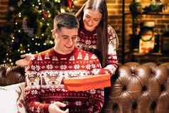 年轻的女人覆盖眼睛微笑好奇的丈夫给包装盒子圣诞节礼物装饰节日树一年冬天假期家庭庆祝活动假期奇迹