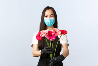 小业务冠状病毒流感大流行订单商店概念微笑有吸引力的女花店商店老板员工医疗面具保护手套给客户购买花束