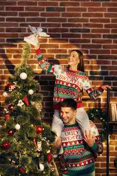 快乐夫妇准备一年冬天假期庆祝活动概念年轻的夫妇装修圣诞节树创建节日情绪大气现代舒适的房子