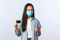社会距离生活方式科维德流感大流行非接触式购物概念可爱的十几岁的亚洲女孩医疗面具显示信贷卡移动电话使订单