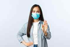 社会距离生活方式科维德流感大流行日常生活休闲概念严肃的表情亚洲女孩显示停止手势距离冠状病毒穿医疗面具