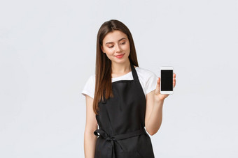 杂货店商店员工小业务咖啡商店概念漂亮的年轻的女咖啡馆工人黑色的围裙做广告移动应用程序显示智能手机屏幕站白色背景