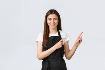 小业务员工咖啡商店概念快乐的微笑漂亮的女服务员显示可爱的女售货员黑色的围裙指出上角落里特殊的促销
