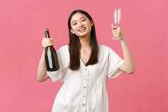 庆祝活动聚会，派对假期有趣的概念快乐的快乐亚洲女孩准备好了享受休假日女朋友带香槟眼镜微笑相机站乐观的粉红色的背景