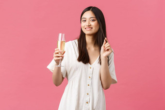 庆祝活动聚会，派对假期有趣的概念优雅的漂亮的年轻的女人参加事件喝香槟微笑快乐享受庆祝站白色衣服粉红色的背景