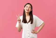 美人情绪夏天休闲概念热情的快乐日本女孩笑微笑显示卡哇伊和平标志白色可爱的衣服粉红色的背景