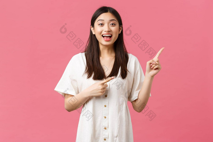 美人情绪夏天休闲假期概念兴奋激动可爱的日本女孩指出手指上角落里站粉红色的背景白色衣服