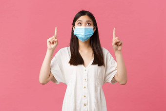 科维德社会距离病毒生活方式概念好奇的漂亮的亚洲女孩医疗面具夏天衣服指出手指促销广告粉红色的背景
