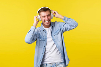 生活方式夏天假期技术概念兴奋英俊的金发碧眼的的家伙听音乐耳机微笑广泛的跳舞节奏首歌站黄色的背景