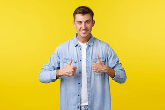 英俊的微笑金发碧眼的男人。显示竖起大拇指鼓励人加油很高兴的家伙推荐产品离开积极的反馈批准服务黄色的背景