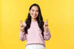 人情绪生活方式时尚概念充满希望的乐观可爱的亚洲女孩高希望交叉手指好运气微笑使站黄色的背景
