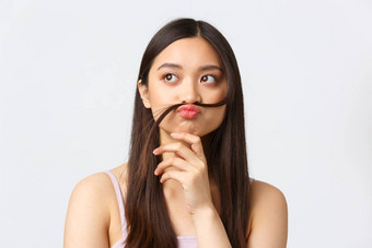概念美时尚化妆产品广告特写镜头肖像有趣的可爱的亚洲女孩思考把头发海滩唇胡子思考的想法白色背景