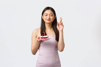 庆祝活动聚会，派对假期概念快乐梦幻美丽的亚洲女人衣服交叉手指好运气关闭眼睛微笑使生日蛋糕白色背景