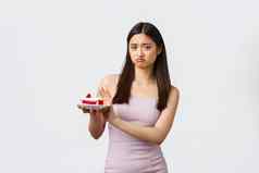 生活方式假期庆祝活动食物概念悲观的心烦意乱亚洲女孩衣服拒绝一块蛋糕撅嘴脸拒绝吃糖果避免甜点完整的卡路里白色背景