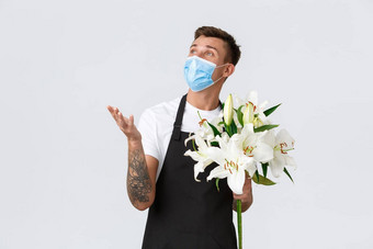 冠状病毒社会距离业务科维德流感大流行概念友好的有魅力的花店充满激情的描述花束销售花持有白色百合穿医疗面具