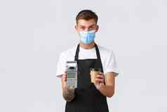 冠状病毒社会距离咖啡馆餐厅业务流感大流行概念英俊的咖啡师医疗面具给订单客户端将回来终端外卖咖啡