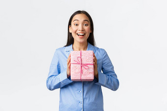 首页假期生活方式概念快乐很高兴微笑亚洲女孩收到生日现在家庭持有礼物穿睡衣解压缩礼物圣诞节夏娃白色背景