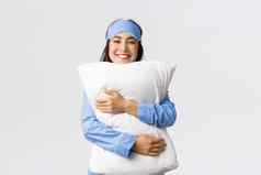 微笑很高兴亚洲女孩睡觉面具睡衣拥抱软舒适的枕头满意放松表达式床上感觉舒适的白色背景