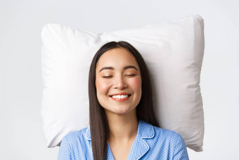 微笑梦幻美丽的亚洲女说谎床上枕头穿蓝色的睡衣关闭眼睛咧着嘴笑做白日梦睡觉晚上成像可爱的白色背景