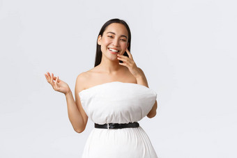 美时尚社会媒体概念漂亮的快乐亚洲女人笑爱炫耀的人装使枕头带摆姿势枕头衣服白色背景