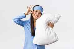 满意快乐微笑可爱的亚洲女孩蓝色的睡衣睡觉眼膜拥抱枕头面具显示手势推荐产品药物治疗睡眠白色背景