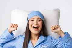 特写镜头热情的亚洲女孩蓝色的睡衣睡觉面具伸展运动手很高兴好晚上睡眠起飞眼膜早....说谎床上枕头微笑快乐