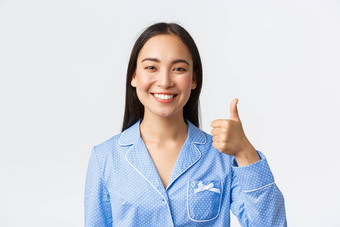 特写镜头满意漂亮的微笑亚洲女人蓝色的睡衣显示竖起大拇指批准推荐保证<strong>产品质量</strong>站很高兴白色背景