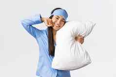 很高兴美丽的亚洲女孩蓝色的睡衣睡觉面具说谎床上拥抱枕头微笑满意度伸展运动感觉好晚上睡眠白色背景
