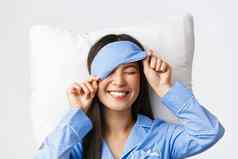 很高兴快乐微笑朝鲜文女孩蓝色的睡衣睡觉面具伟大的一天床上完美的情绪准备好了睡眠说谎枕头乐观的白色背景