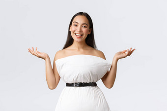 华丽的微笑有创意的亚洲女人创建衣服枕头抓牢带浪费提高手咧着嘴笑显示装站白色背景