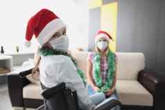 年轻的女人访问朋友医院相对轮椅脸面具保护