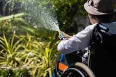 高级女人手持有软管喷雾器浇水植物后院