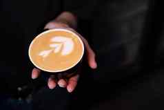 手持有热咖啡杯花形状拿铁咖啡艺术咖啡房子概念咖啡爱